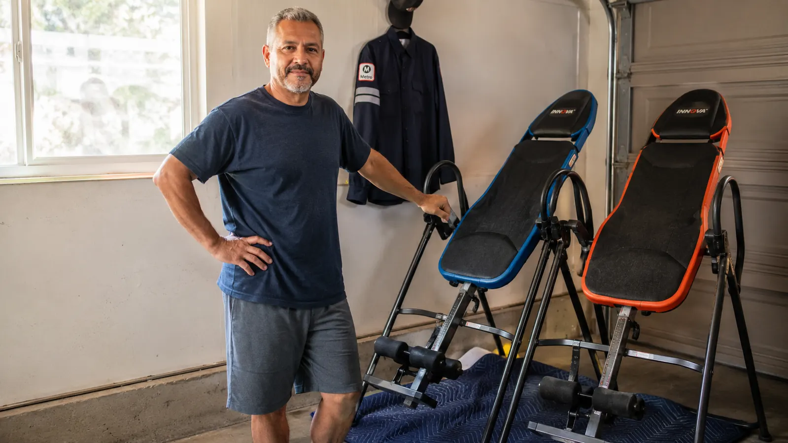 Two inversion tables set up side by side in a garage workout corner, one visibly more compact than the other